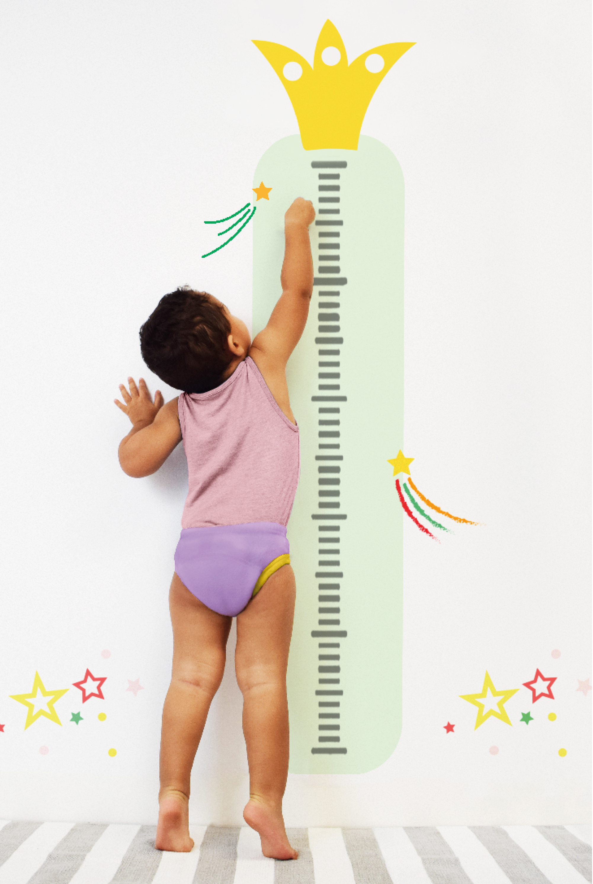 Child standing next to a height chart with a crown on a white wall.