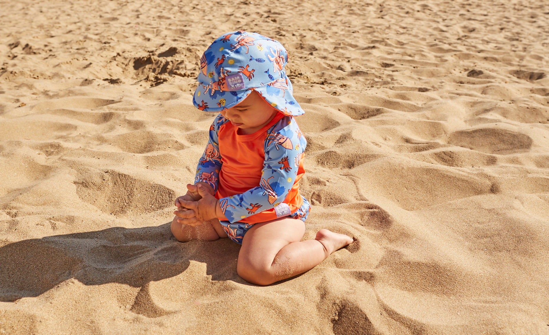 Reusable swim nappy, sun sat and rash vest being worn by a child at the beach